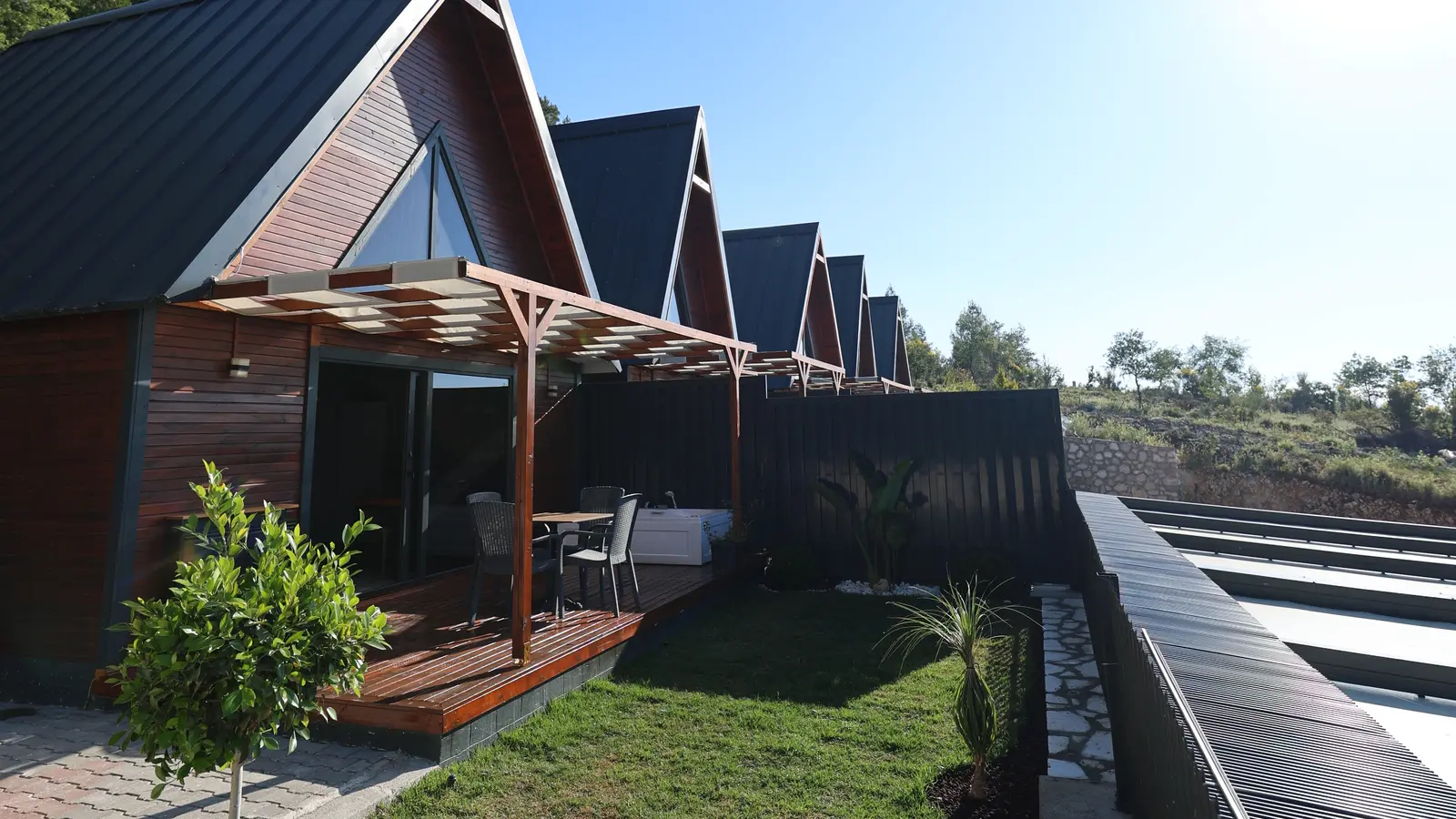 Üçgen çatılı ahşap bungalovlar ve dağ manzarası